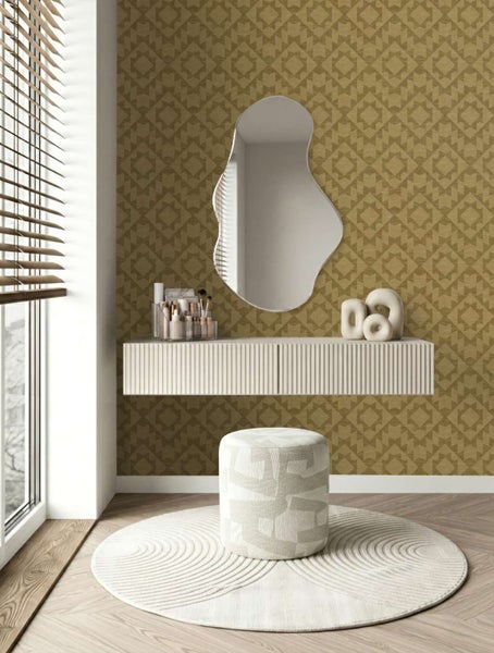Wand mit geometrischer Mustertapete in einem Schlafzimmer mit Frisiertisch, Spiegel, Sitzhocker und rundem Teppich auf Holzboden.