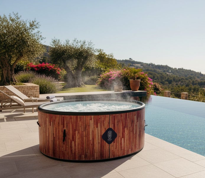Aufblasbarer Whirlpool in Holzoptik auf einer Terrasse neben einem Pool, im Hintergrund ein Garten mit Olivenbäumen.