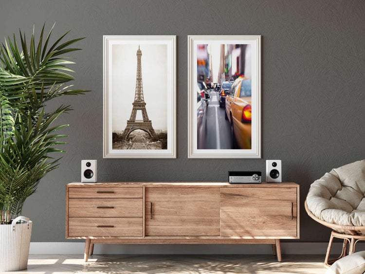 Helles, modern eingerichtetes Wohnzimmer mit zwei großen gerahmten Bildern über einem Sideboard aus Holz und einer großen Zimmerpflanze.