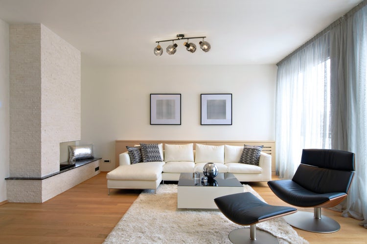 Helles Wohnzimmer mit Sofa, Sessel, Couchtisch und Kamin