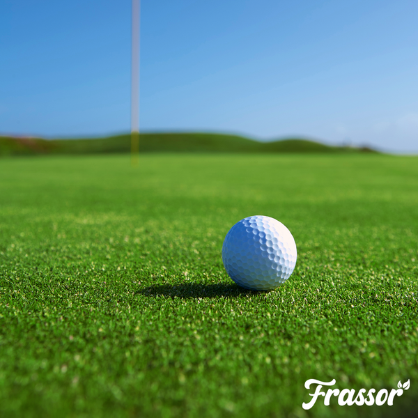 Golfball auf einem gepflegten Rasen auf einem Golfplatz mit Frassor Logo.