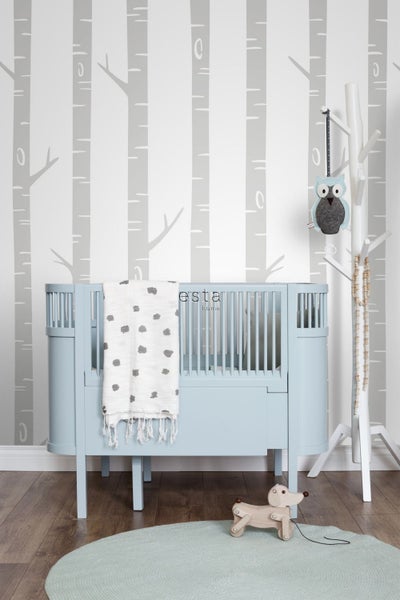 Kinderzimmer mit blauem Kinderbett, Holzspielzeug und Baumtapete