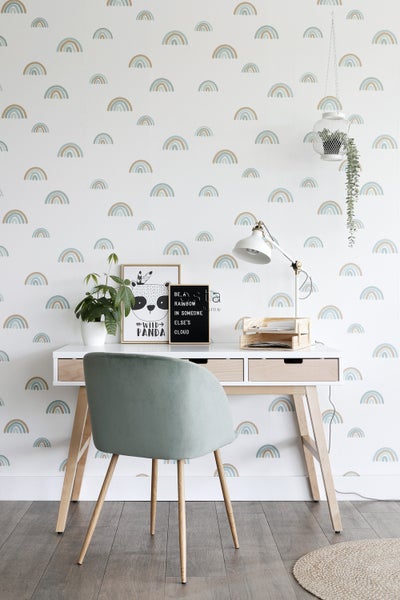 Heller Arbeitsbereich mit Schreibtisch, Stuhl und Regenbogen-Tapete für eine freundliche Atmosphäre.
