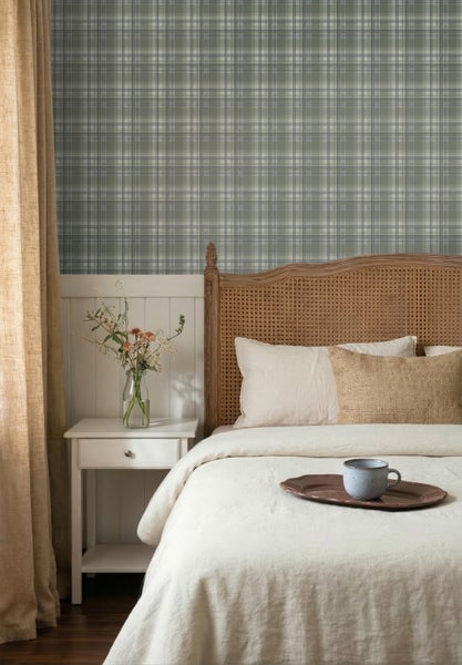 Schlafzimmer mit karierter Tapete in Grün und Grau, Holzbett mit Kopfteil aus Wiener Geflecht, weißen Wandpaneelen und einem weißen Nachttisch.