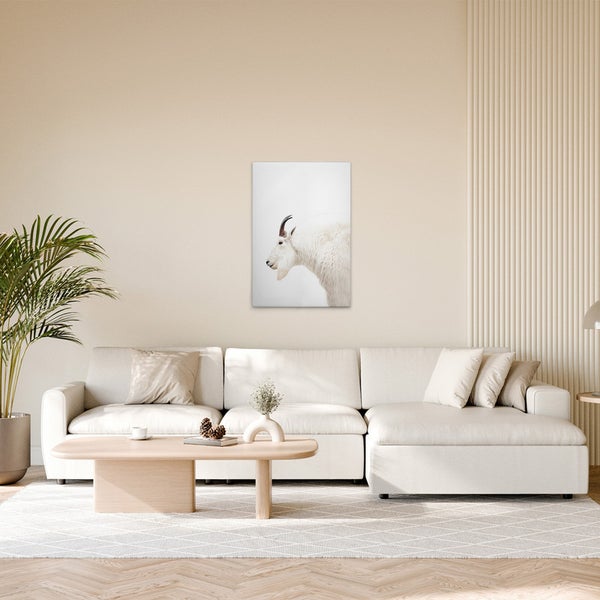 Gemütliches Wohnzimmer mit Sofa, Tisch und einem Wandbild eines Bergziegenportraits.