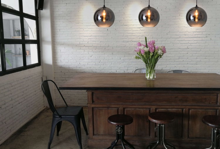 Helle Raumszene mit Holztisch, Stühlen und Pendelleuchten