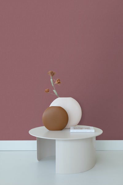 Dekoratives Stillleben mit Tisch, Vasen, Buch und Wandtapete.