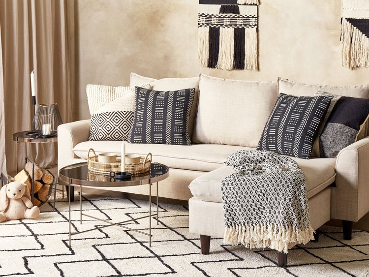 Wohnzimmer mit Sofa, Kissen, Decke, Teppich und Beistelltischen