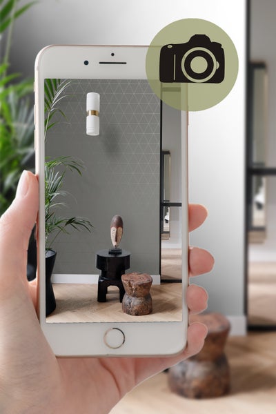 Aufnahme eines Raumes mit Wandleuchte, Dekoration und Möbeln auf einem Smartphone.