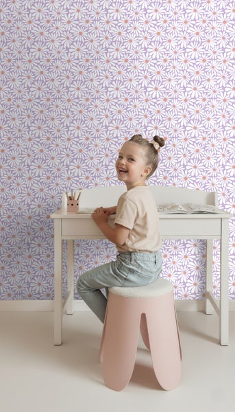 Mädchen am Schreibtisch vor einer Wand mit Gänseblümchen Tapete