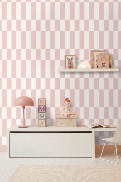 Kinderzimmer mit Vliestapete im rosa-weißen Schachbrettmuster, hellem Sideboard, Wandregal und Accessoires.