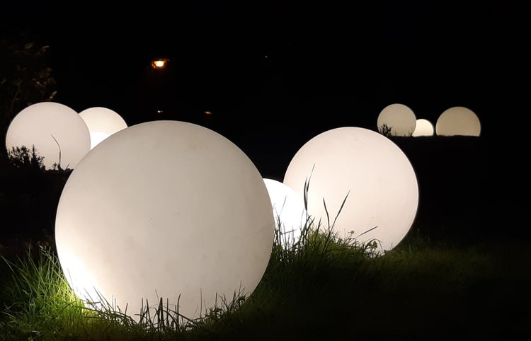 Mehrere beleuchtete Kugellampen im Gras
