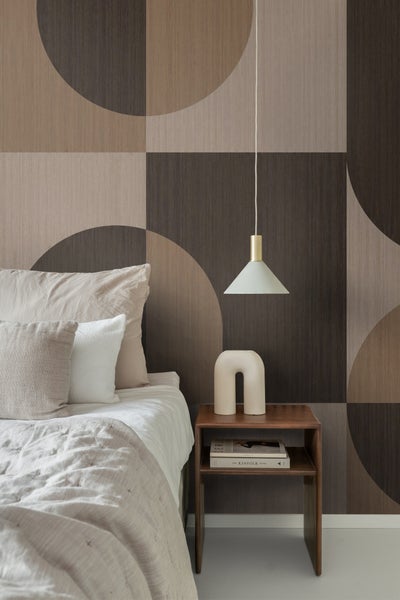 Schlafzimmer mit Bett, Nachttisch und Wandtapete mit geometrischem Muster