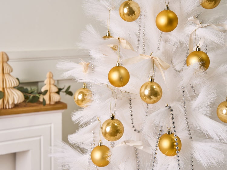 Geschmückter weißer Weihnachtsbaum mit goldenen Kugeln und silbernen Perlenketten.