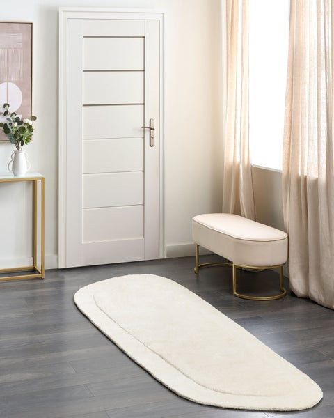 Innenraumszene mit einem weißen Teppich, einer weißen Tür, einem Hocker und einem Beistelltisch.