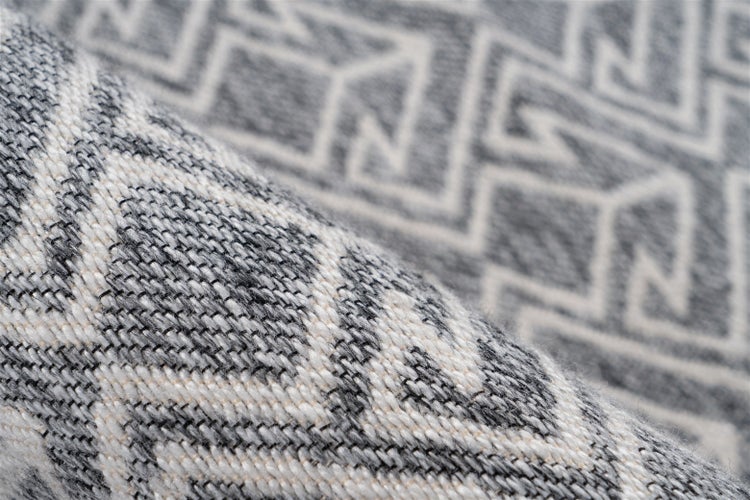 Nahaufnahme eines gewebten Teppichs mit geometrischem Muster, die die Textur und das Gewebe zeigt.