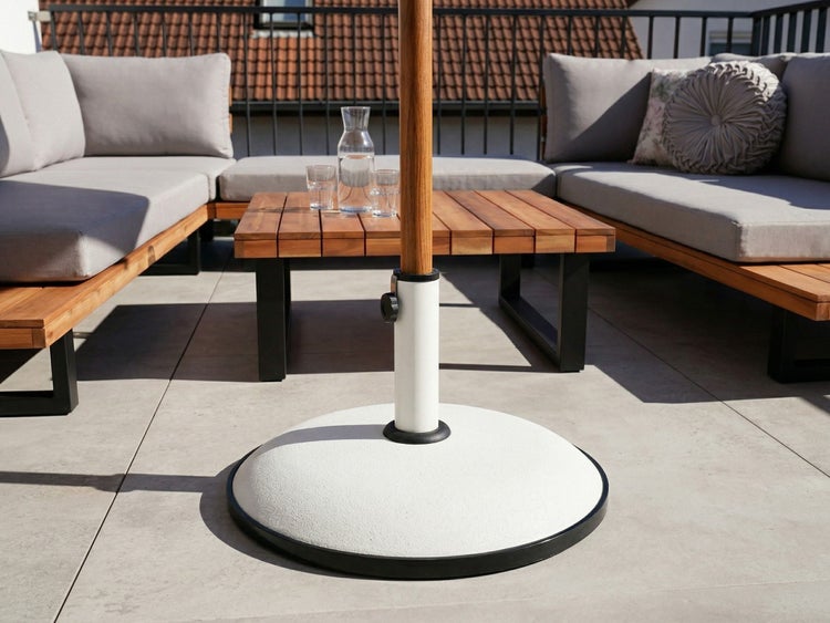 Runder Sonnenschirmständer aus Beton auf einer modernen, hellen Dachterrasse mit Loungemöbeln aus Holz.