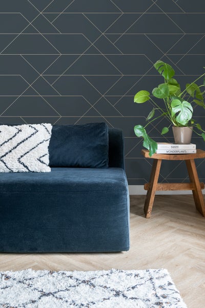 Wohnzimmer mit Sofa, Zimmerpflanze und geometrischer Tapete