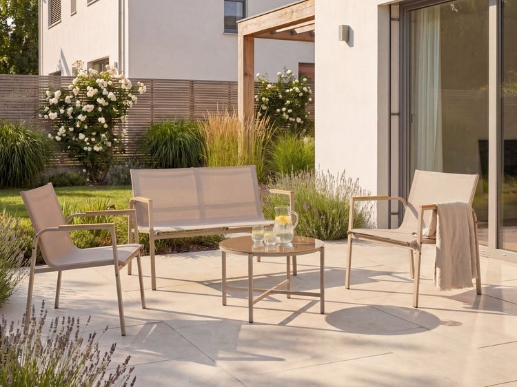 Moderne beige Gartenlounge aus Metall und Textil, bestehend aus Bank, zwei Sesseln und Tisch auf einer hellen, aufgeräumten Terrasse.