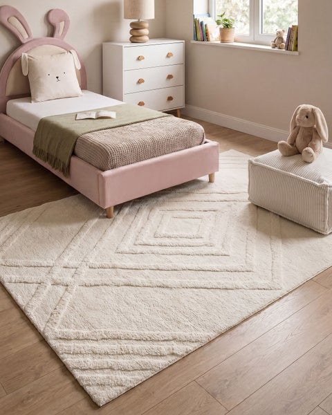 Ein gemütliches Kinderzimmer mit einem strukturierten Teppich mit Rautenmuster, einem Hasenbett und einer weißen Kommode auf hellem Holzboden.