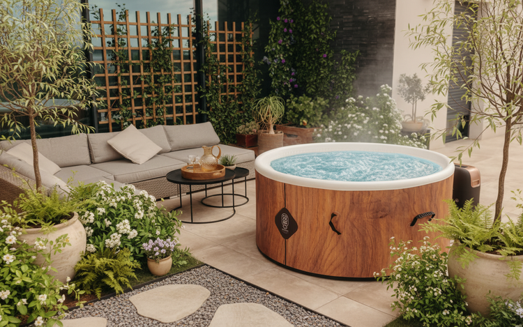 Runder Whirlpool in Holzoptik auf einer modern gestalteten Terrasse mit grauem Lounge-Sofa, schwarzen Beistelltischen und vielen Pflanzen.