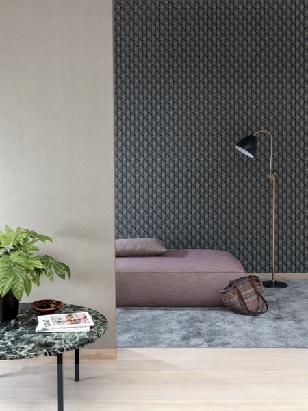 Raumansicht mit gemusterter Tapete, Liege, Stehlampe und Beistelltisch