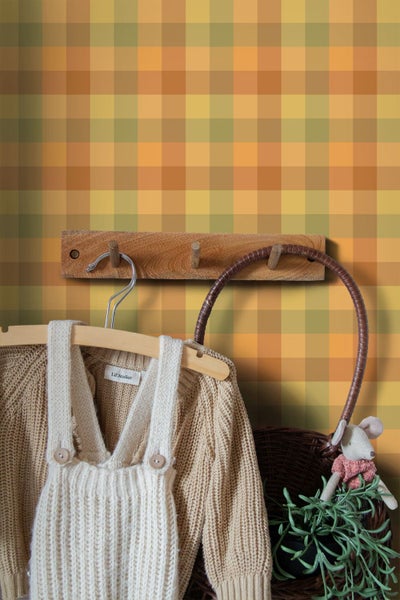 Vliestapete mit großem Karomuster in Erdtönen in einem Kinderzimmer mit Holzgarderobe und Strickkleidung.