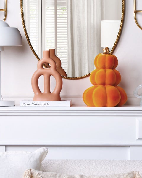 Dekorative Szene auf einem Kaminsims mit Kürbisfigur, Vase und Spiegel