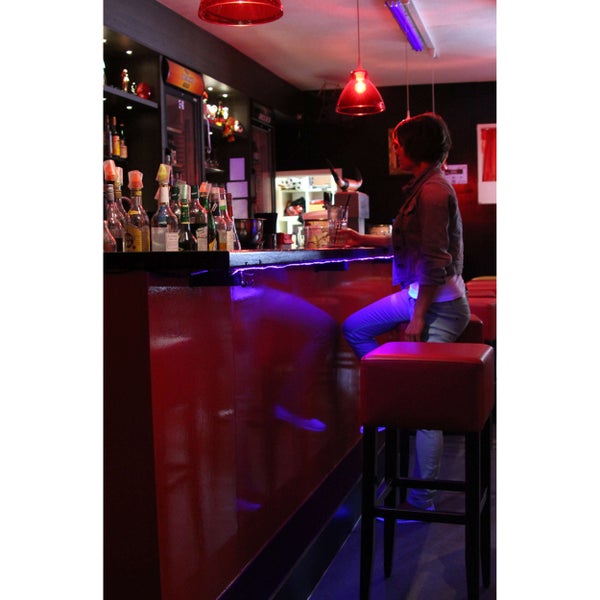 Szene einer Bar mit Tresen, Barhockern und einer Person, die an der Bar sitzt.