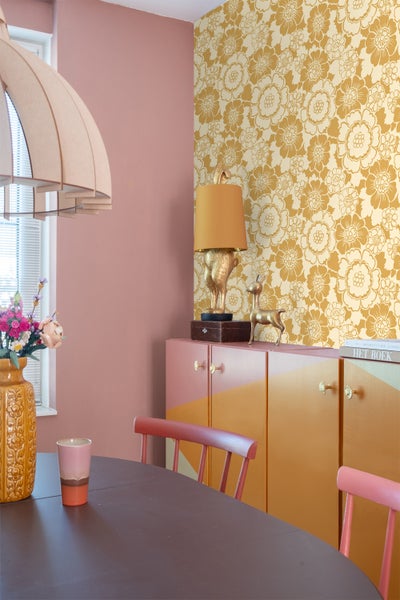 Wohnraum mit Blümchentapete, Anrichte, Tisch und Stühlen