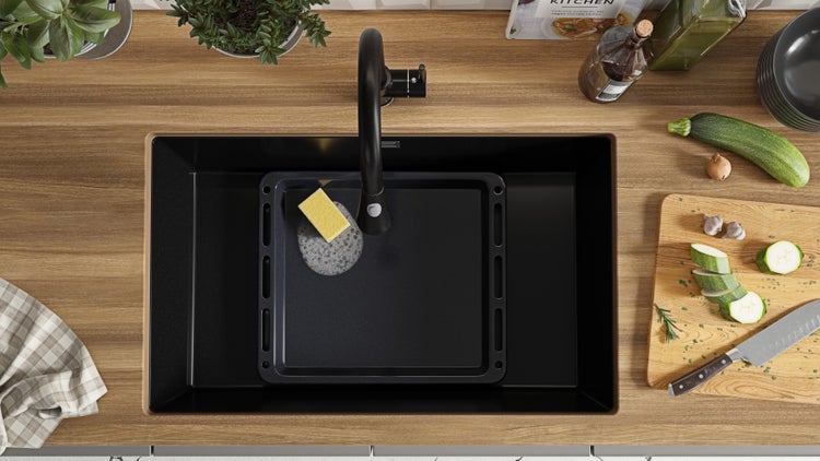 Küchenspüle mit Armatur, Backblech und Lebensmitteln auf einer Arbeitsplatte.