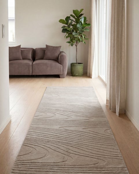 Moderner Läufer mit Holzmaserungsmuster auf hellem Holzfußboden in einem hellen Wohnzimmer mit Sofa und Zimmerpflanze.