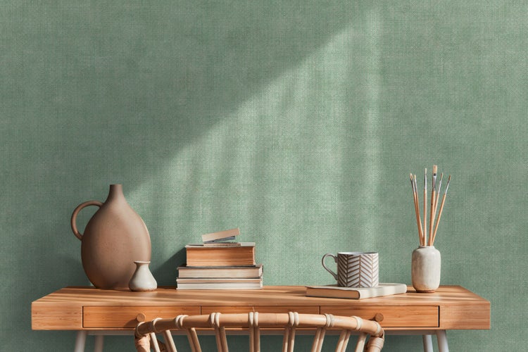 Szene mit Schreibtisch, Dekorationen und Bücherstapel vor einer Wand.