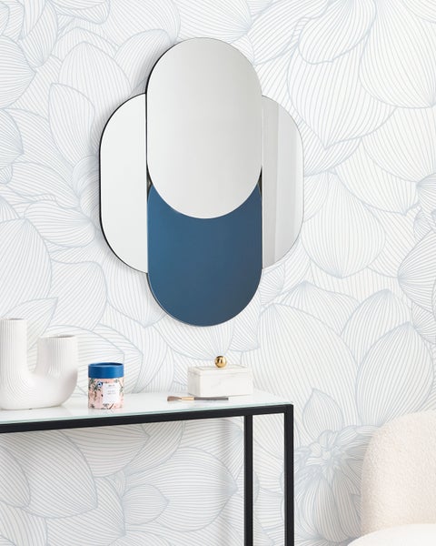 Dekoratives Spiegelarrangement an einer gemusterten Wand, ergänzt durch einen modernen Konsolentisch mit dekorativen Objekten.