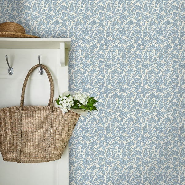 Tapete mit floralem Muster an einer Wand mit Garderobe und Korb. Wandgestaltung im Landhausstil für ein wohnliches Ambiente.