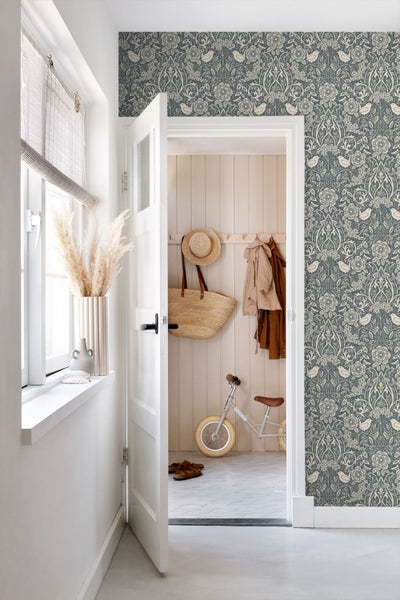 Hell gestalteter Flur im Landhausstil mit gemusterter Tapete mit Vögeln und Blumen, Blick in einen organisierten Eingangsbereich mit Holzpaneelen.