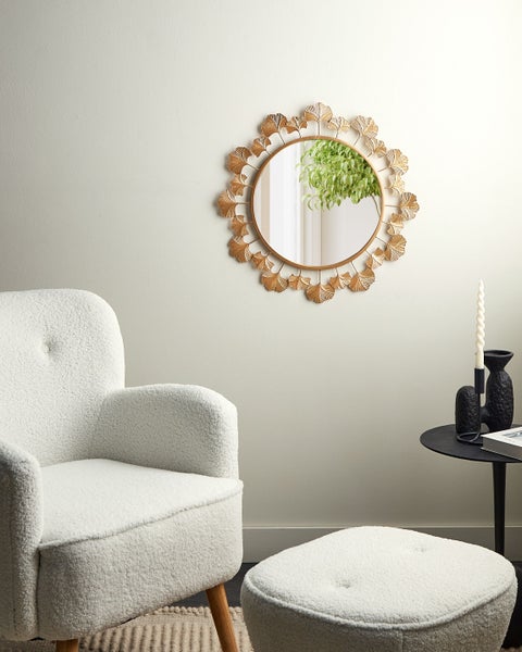 Wohnzimmer mit Sessel, Fußhocker und rundem Spiegel mit Blattdesign