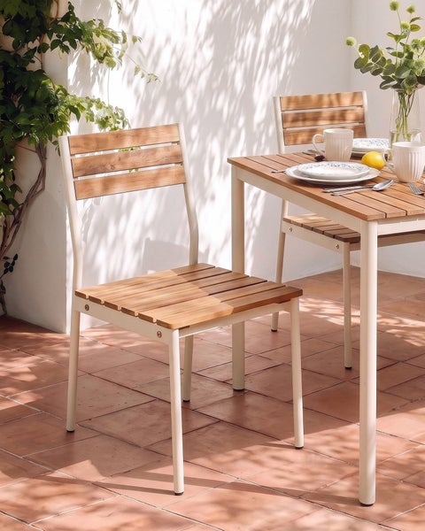 Gartenstuhl mit Holzlatten und Metallgestell auf einer Terrasse mit gedecktem Tisch in heller Umgebung.