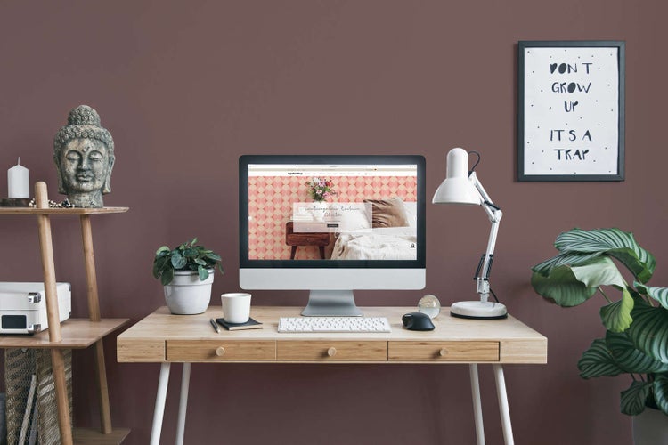 Modernes Arbeitszimmer mit einer in mattem Beerenton gestrichenen Wand, Holztisch, Computer und Dekoration.