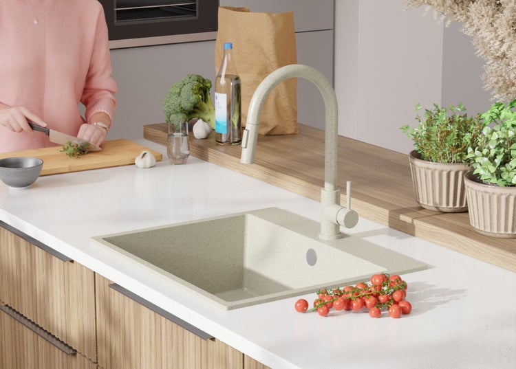 Küchenspüle mit Armatur, Tomaten und einer Person, die Kräuter schneidet