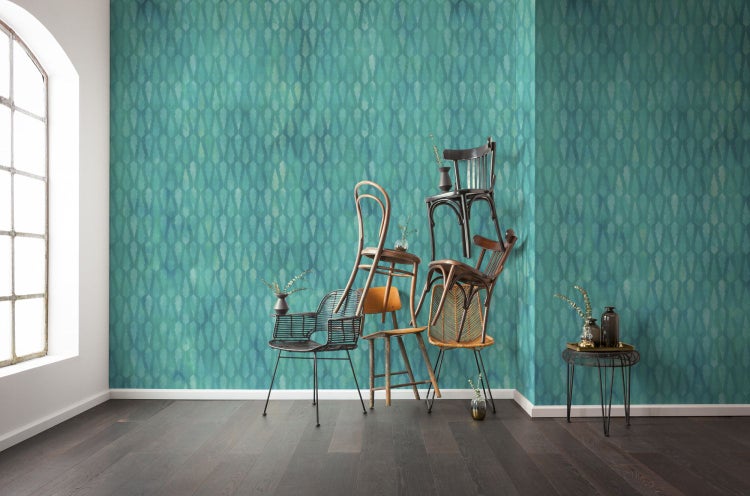 Zimmer mit gemusterter Tapete und verschiedenen Stühlen