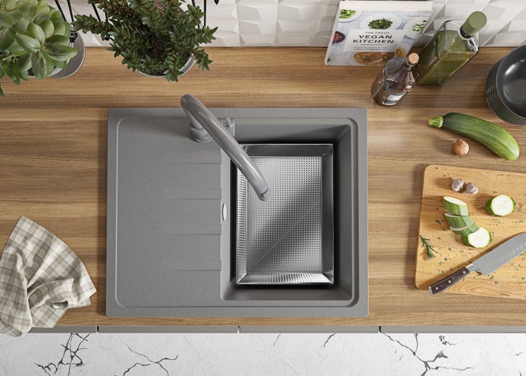 Küchenspüle mit Abtropfschale, Armatur, Schneidebrett und Zutaten auf einer Küchentheke