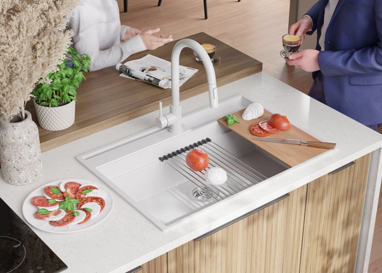 Küchenszene mit Spüle, Abtropfgestell, Schneidebrett mit Zutaten, Teller Caprese, Armatur und zwei Personen