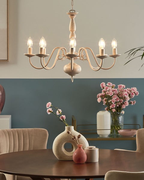 Kronleuchter über Esstisch mit Blumenarrangements