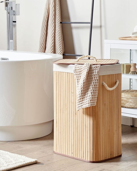 Rechteckiger Wäschekorb aus Bambus mit Deckel und Seilgriffen in einem hellen Badezimmer neben einer weißen Badewanne.