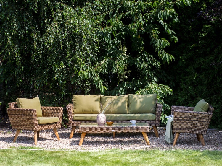 Gartenmöbelset mit Rattansofa, Sesseln und Tisch auf einer Rasenfläche