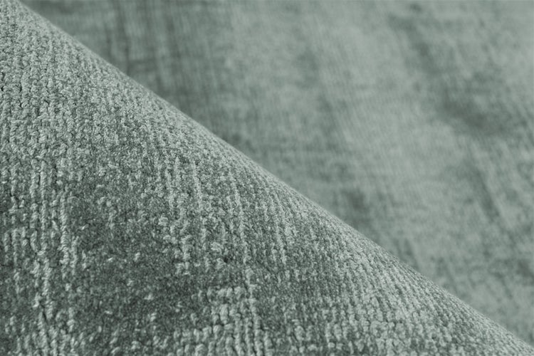 Nahaufnahme der Textur eines kurzflorigen Teppichs in Grün.