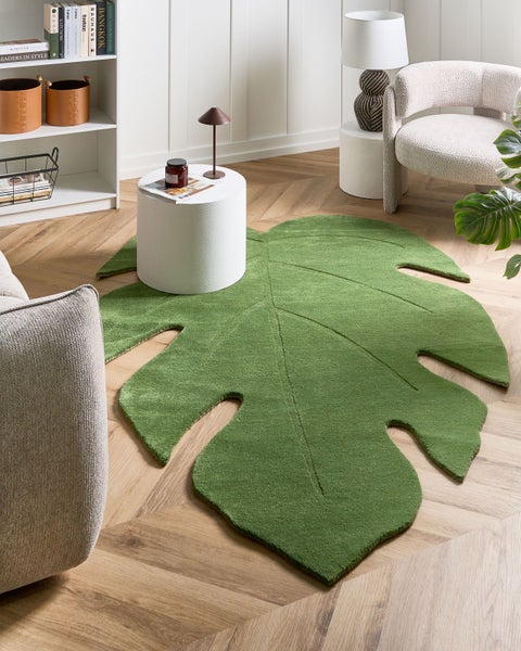 Grüner Teppich in Form eines Monstera-Blattes mit strukturierter Oberfläche.