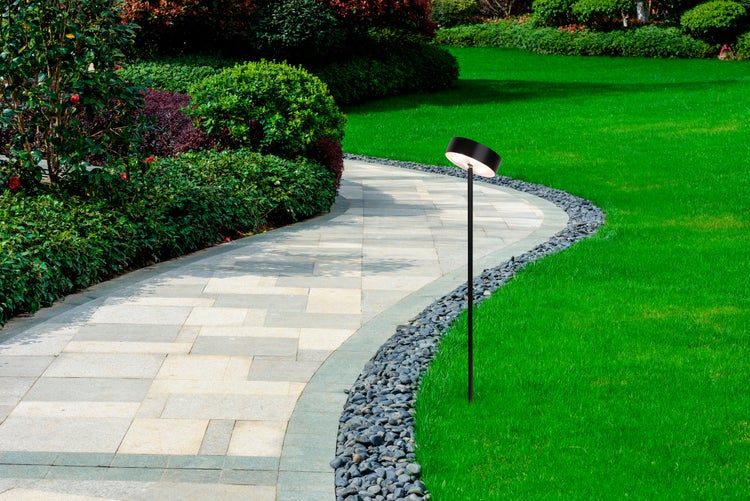 Gartenlandschaft mit Weg, Grünflächen und Wegbeleuchtung