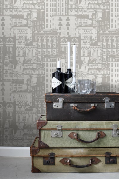 Dekorative Tapete mit Stadtmotiv über einem Stapel Vintage-Koffer